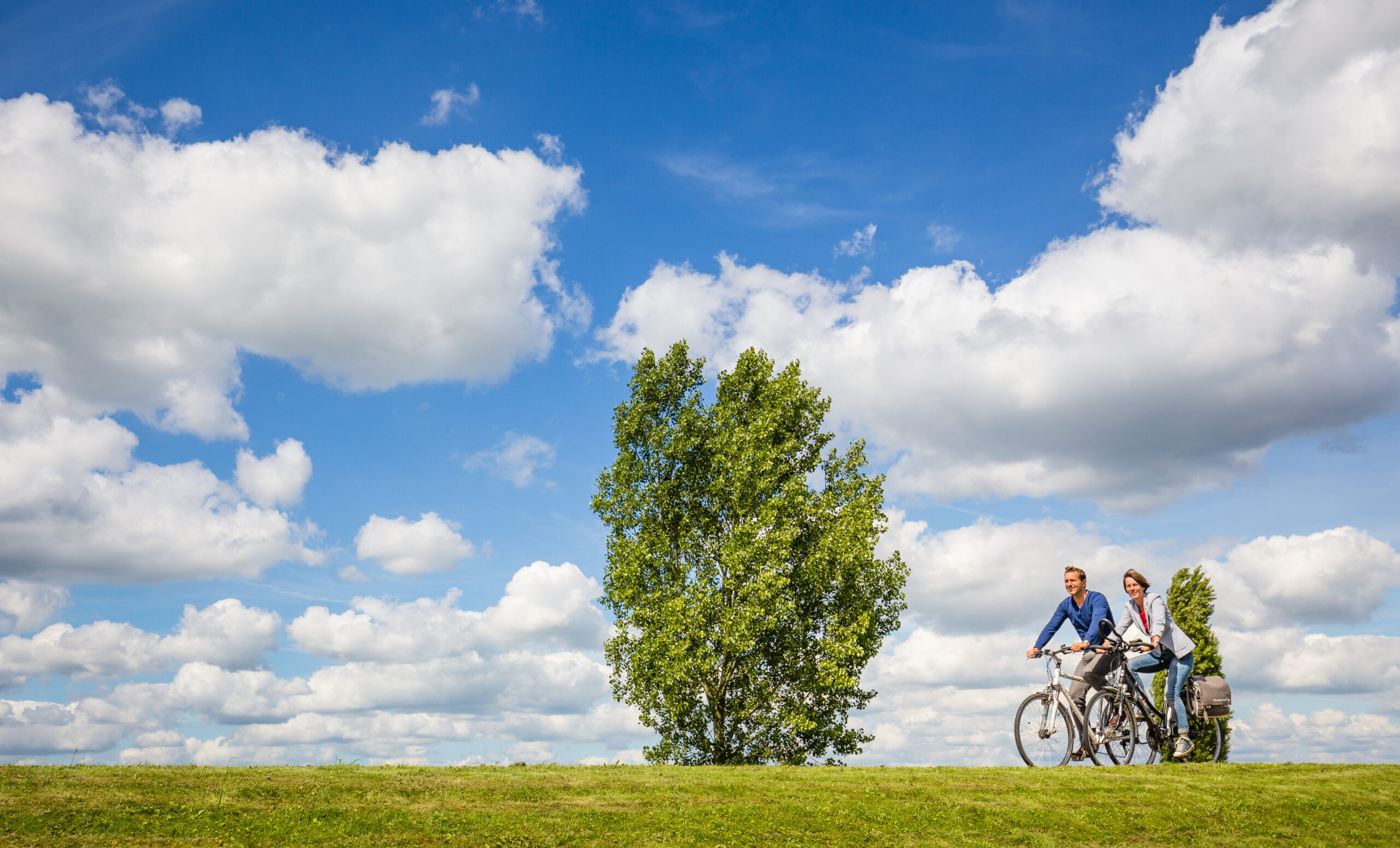 Twee fietsers op een groene dijk