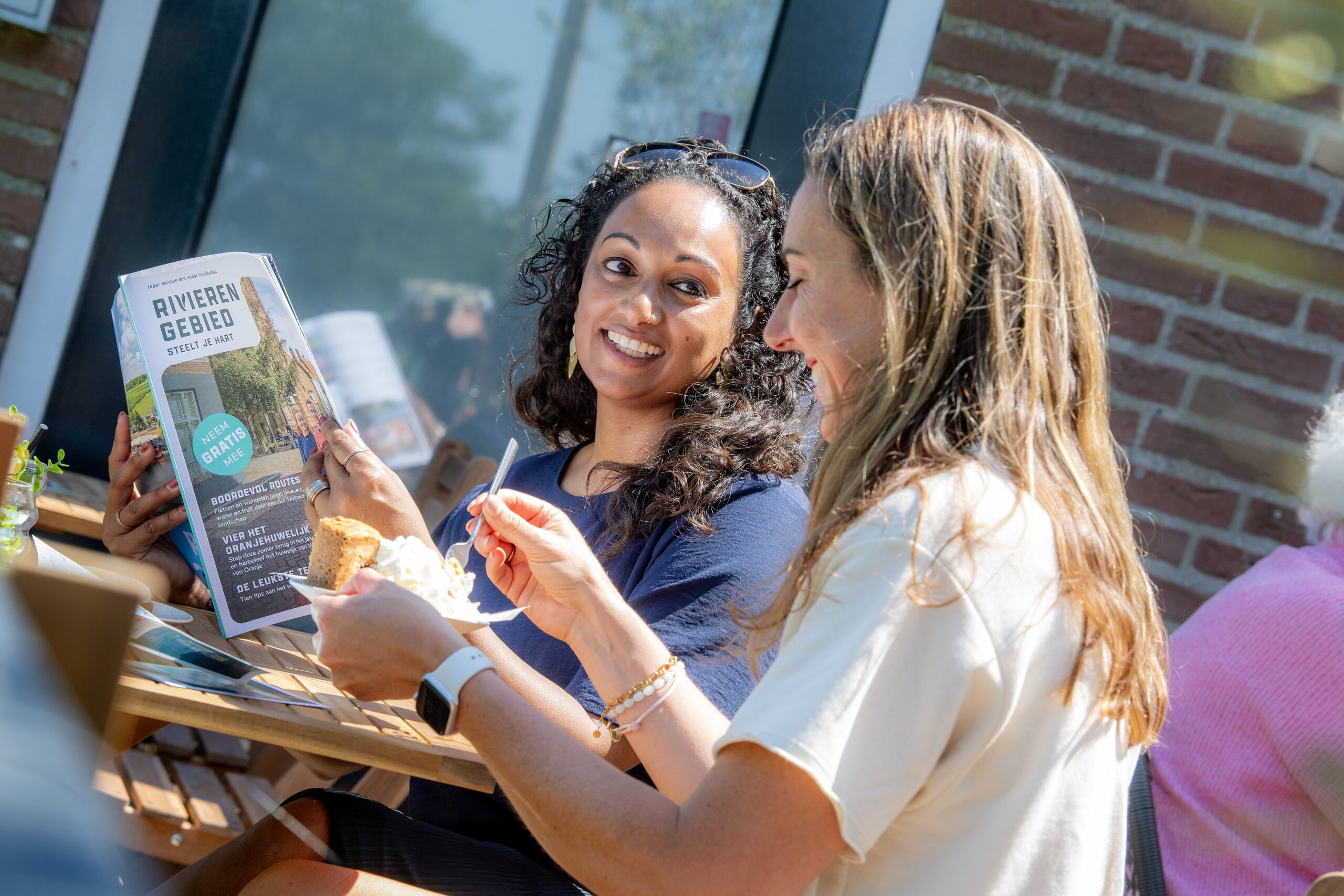 Bezoekers bekijken het Rivierengebied Magazine op een terras