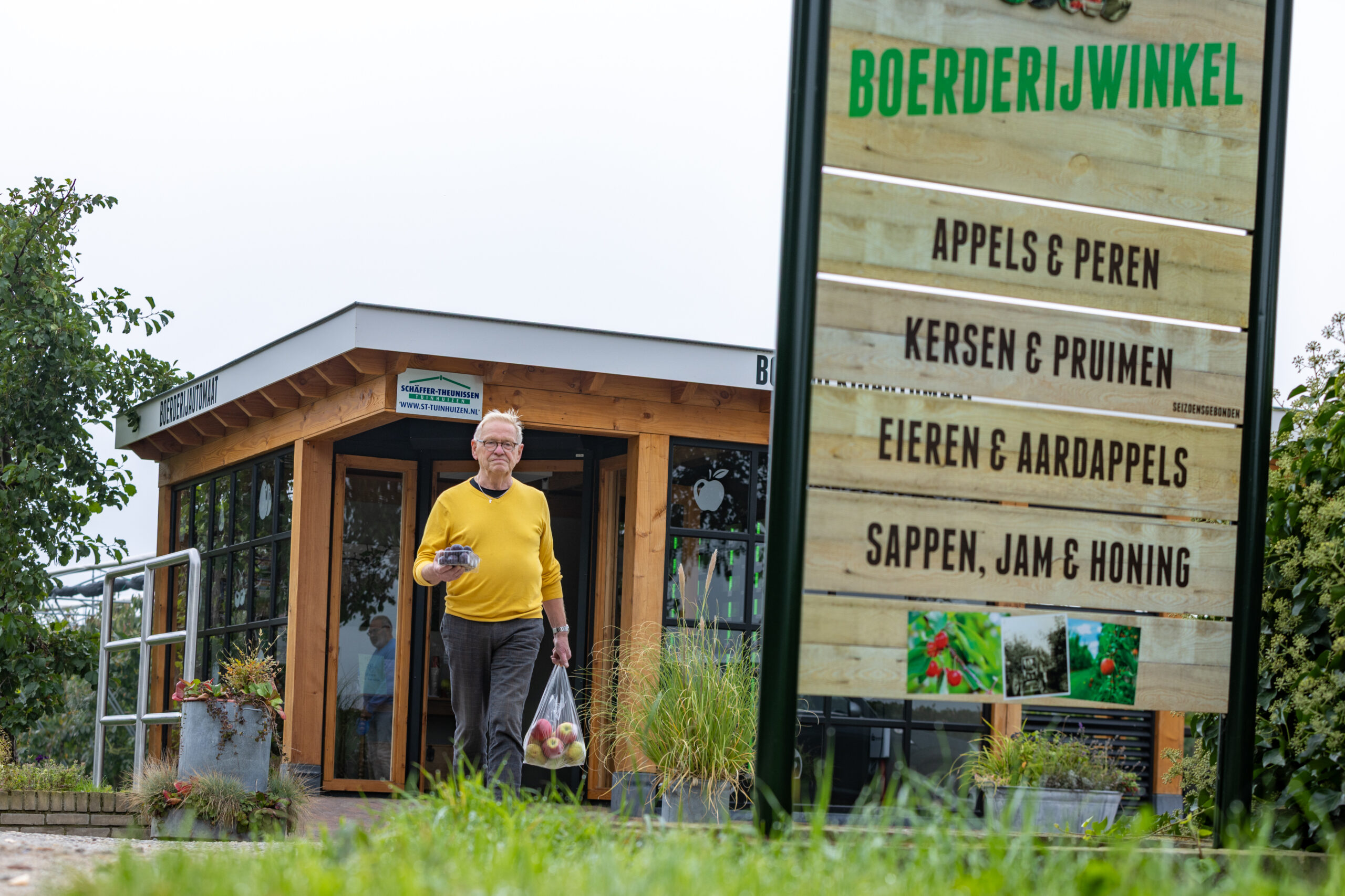 Bezoeker met streekproducten bij de boerderijwinkel van Theunissen en Peters